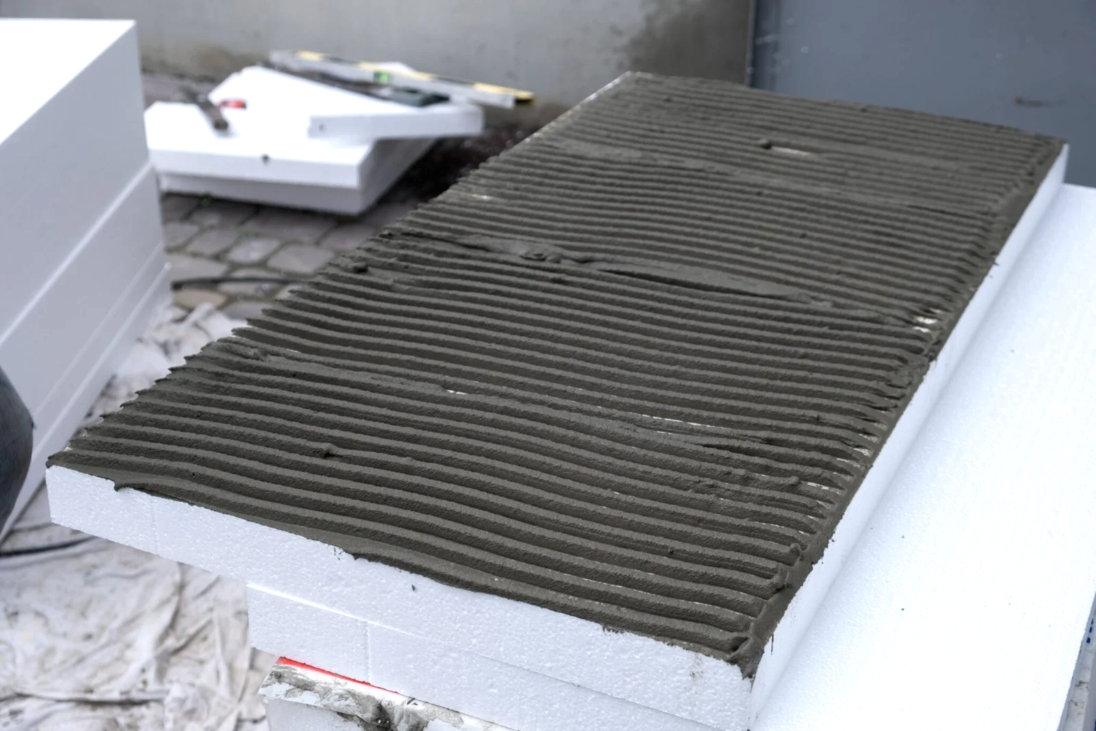 Installation of styrofoam insulation sheets on house facade wall for thermal protection.